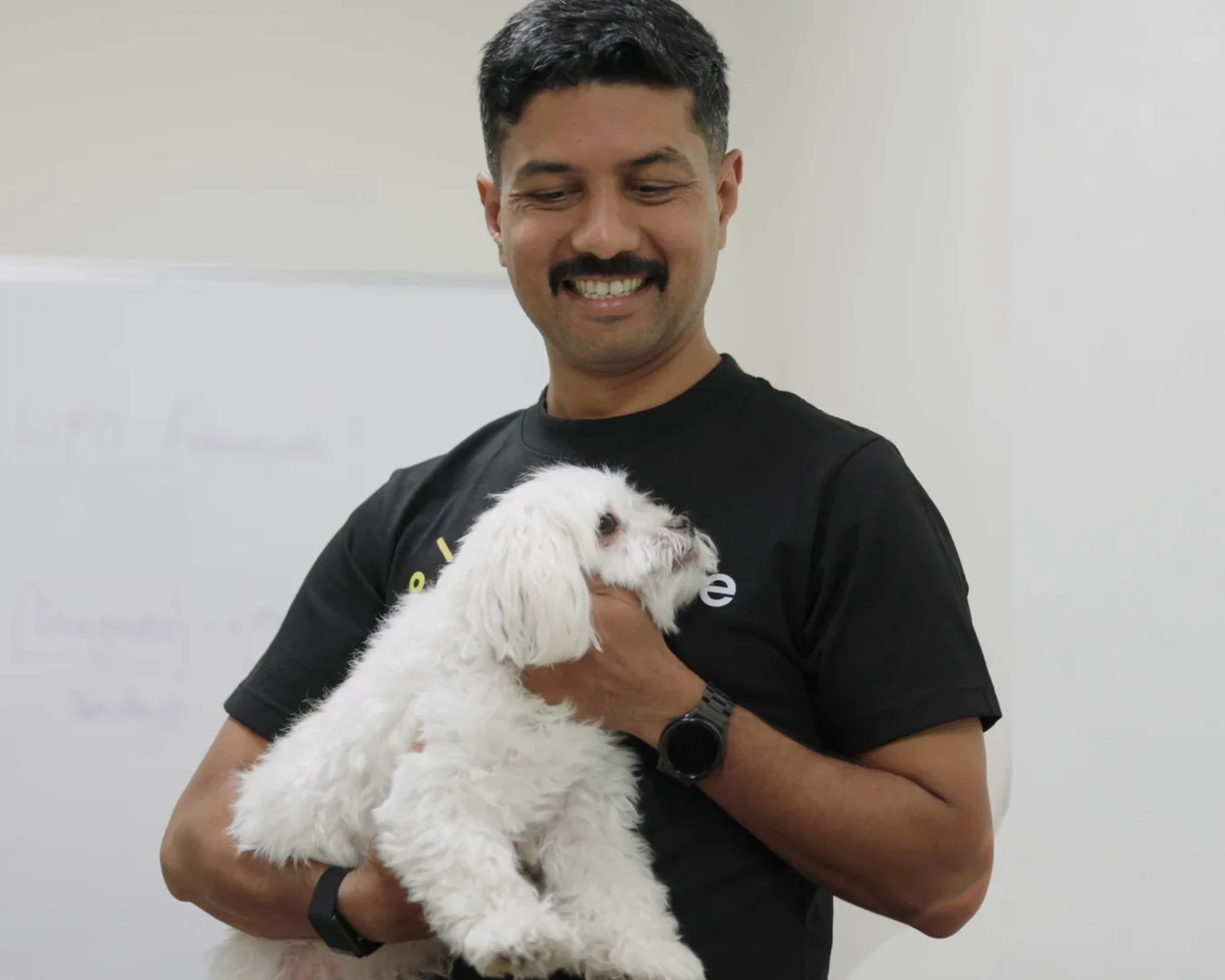 Nirmal Gyanwali smiling as he holds his dog Max in the WP Creative office