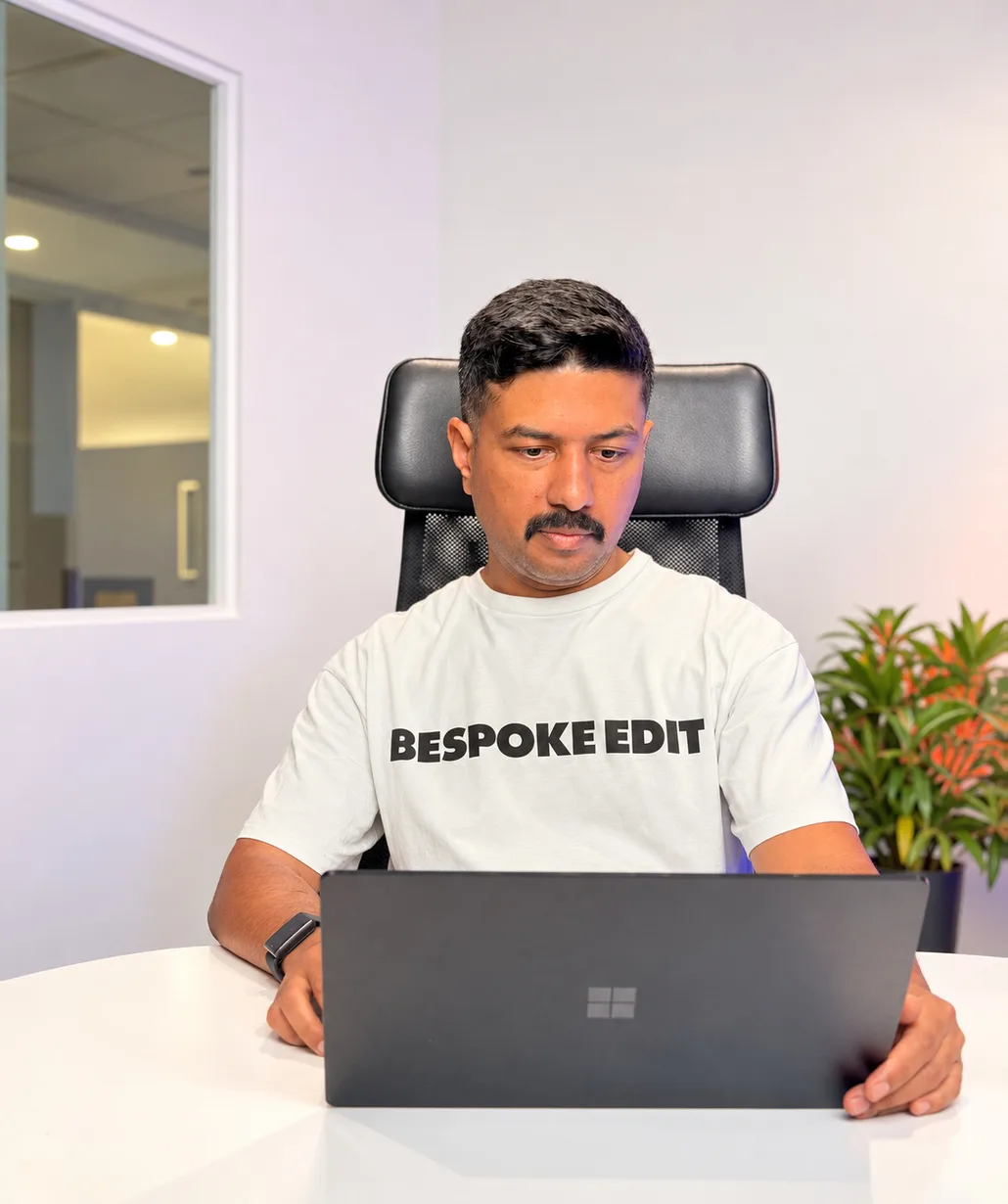 Nirmal Gyanwali working on a laptop in a white T-shirt
