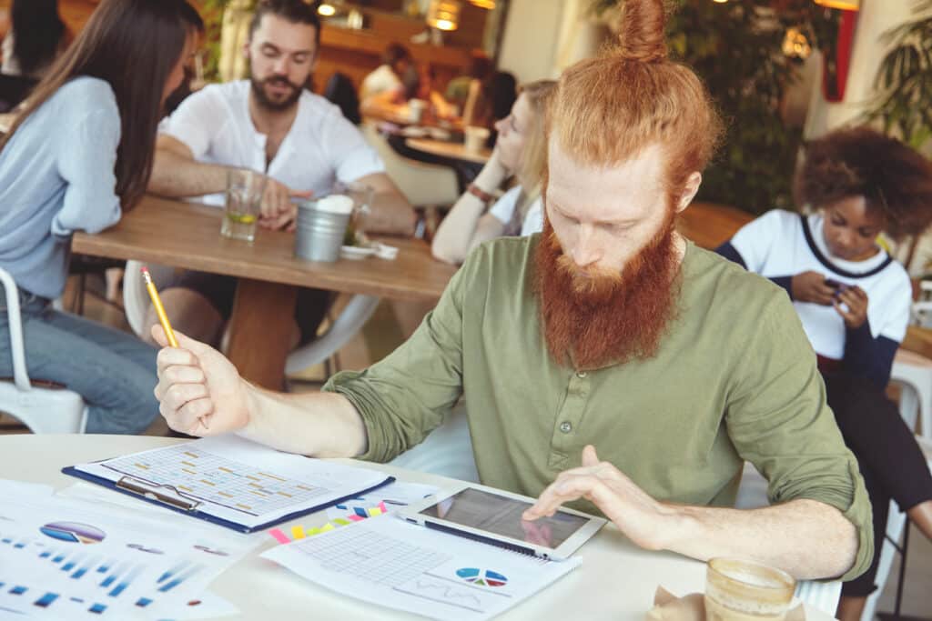 How Much Does It Cost To Start a Small Business? 1 young ginger man using tablet cafe 1